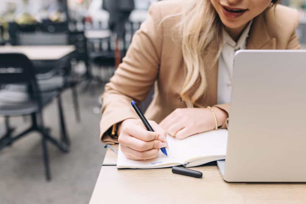 7 Simple Steps for a Successful Goal Setting Process. Woman writing in Notebook.