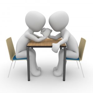 Stock photo of two animated figures arm wrestling at a table